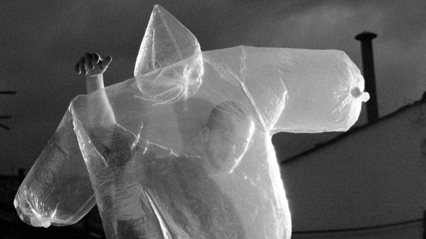 A performer dancing with an inflated piece of translucent white plastic which holds the shape of the top half of a body.