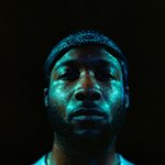 Trinity Laban Rebrand photo. Dancer looks into the camera, beads of sweat across his face, an expression of calm composure.